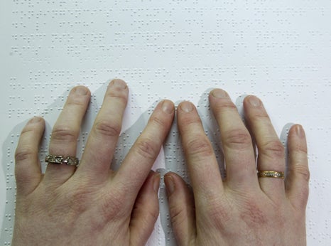 A blind person reads a book written in braille.